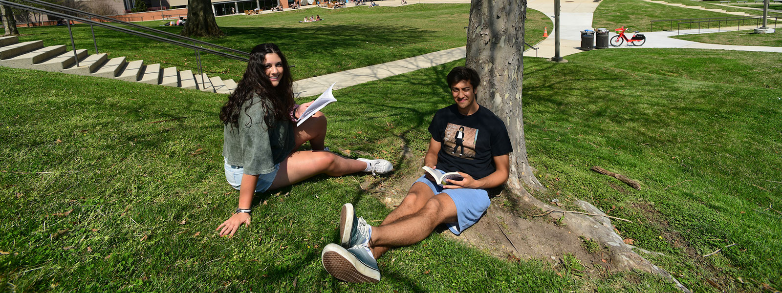 Male and female students sitting on lawn in front of student center